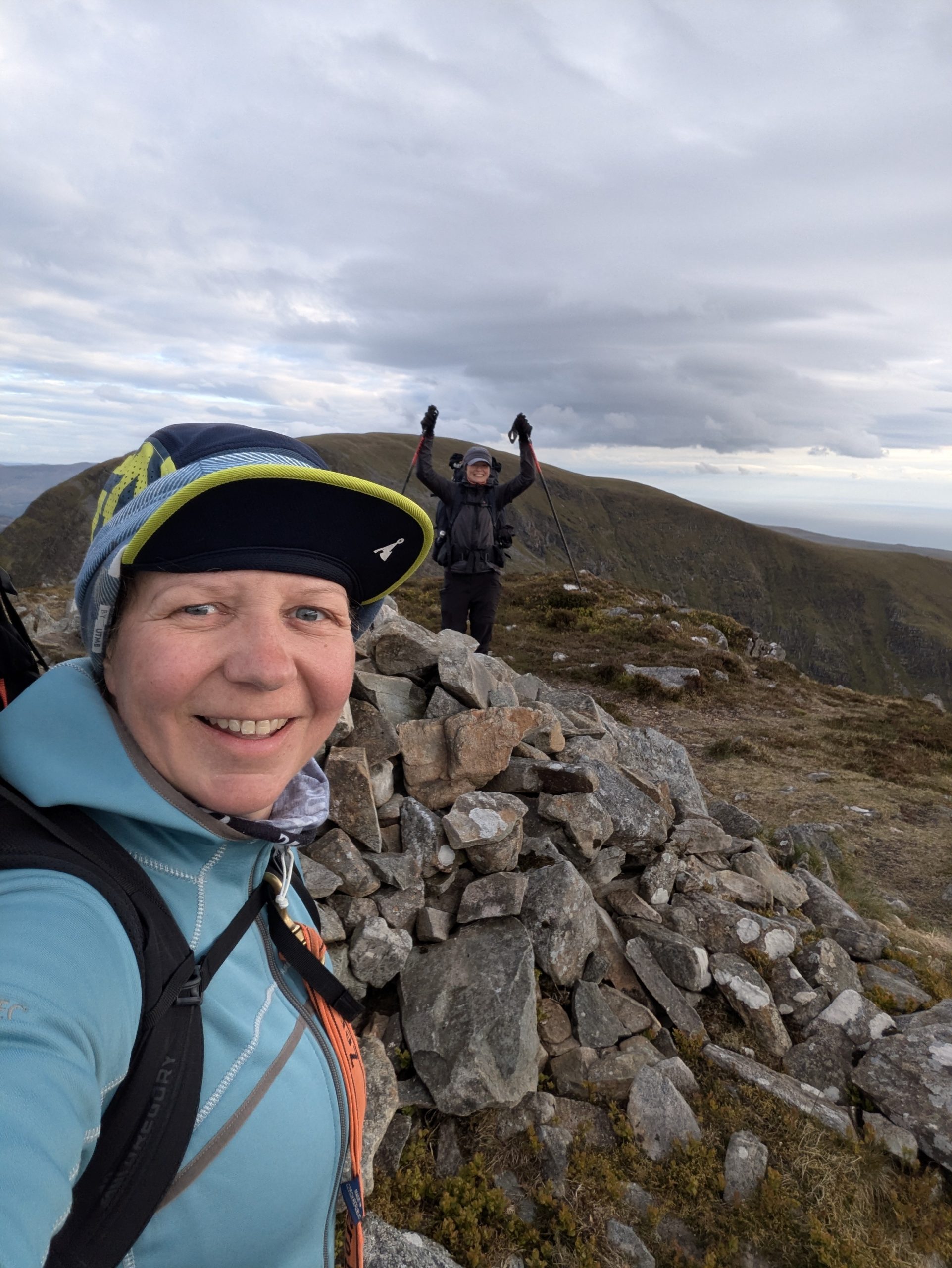 Syla celebrating at a rocky mountain summit during a challenging UK trek