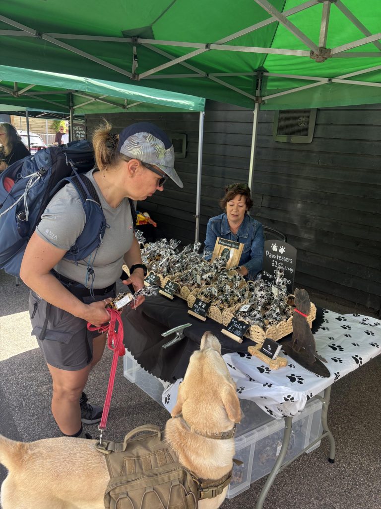 A local market stall outside The Red Lion pub displaying an assortment of natural dog treats.