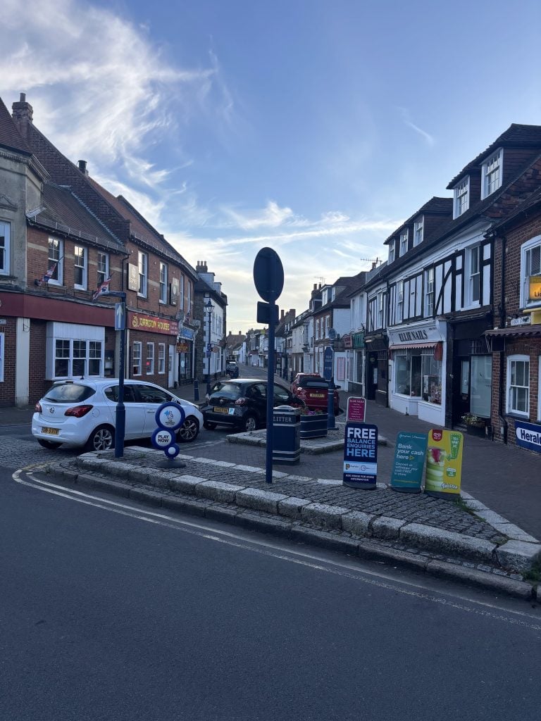 The official Elham Valley Way wooden trail signpost standing on a street corner in Hythe.