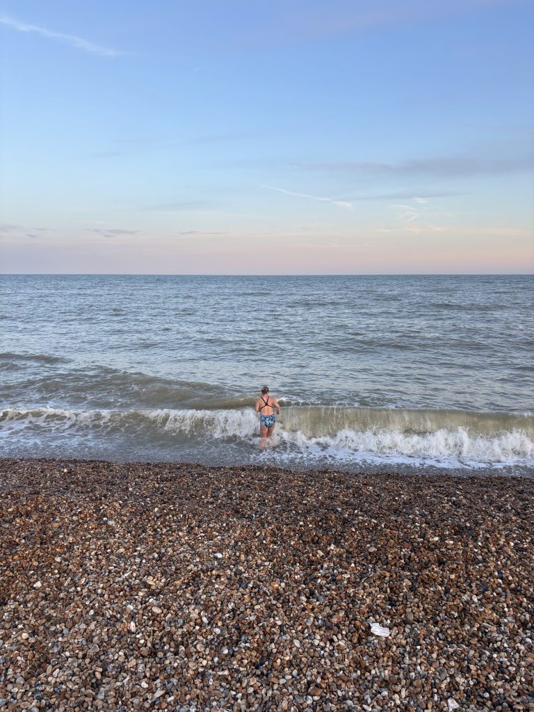 Small, choppy ocean waves crashing gently onto the pebble shore at Hythe beach.