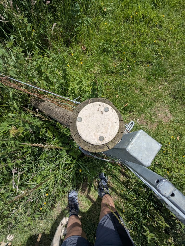 A small, yellow public footpath arrow barely visible attached to a wooden post.