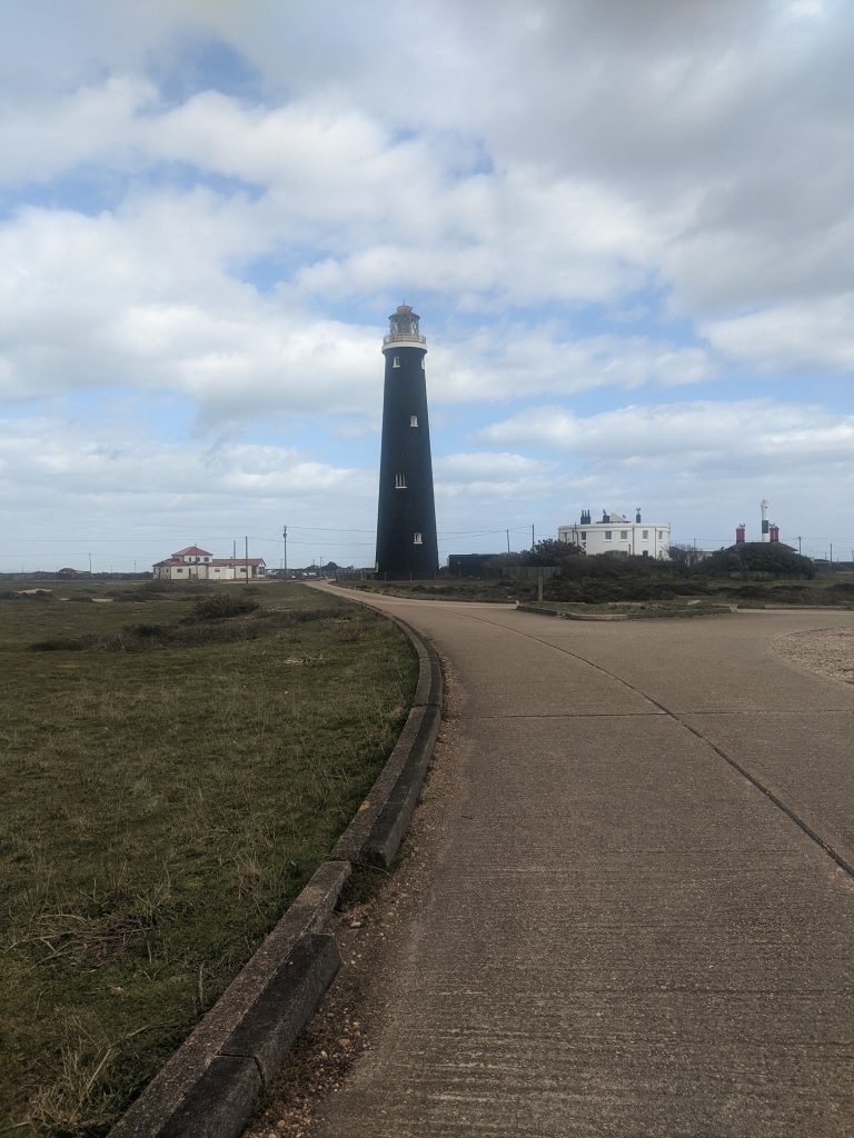 The historic black brick Old Lighthouse standing tall on the flat Dungeness headland in Kent.