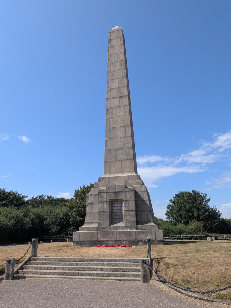 The tall, granite obelisk of the Dover Patrol Memorial standing against a clear blue sky on the Kent coast.
