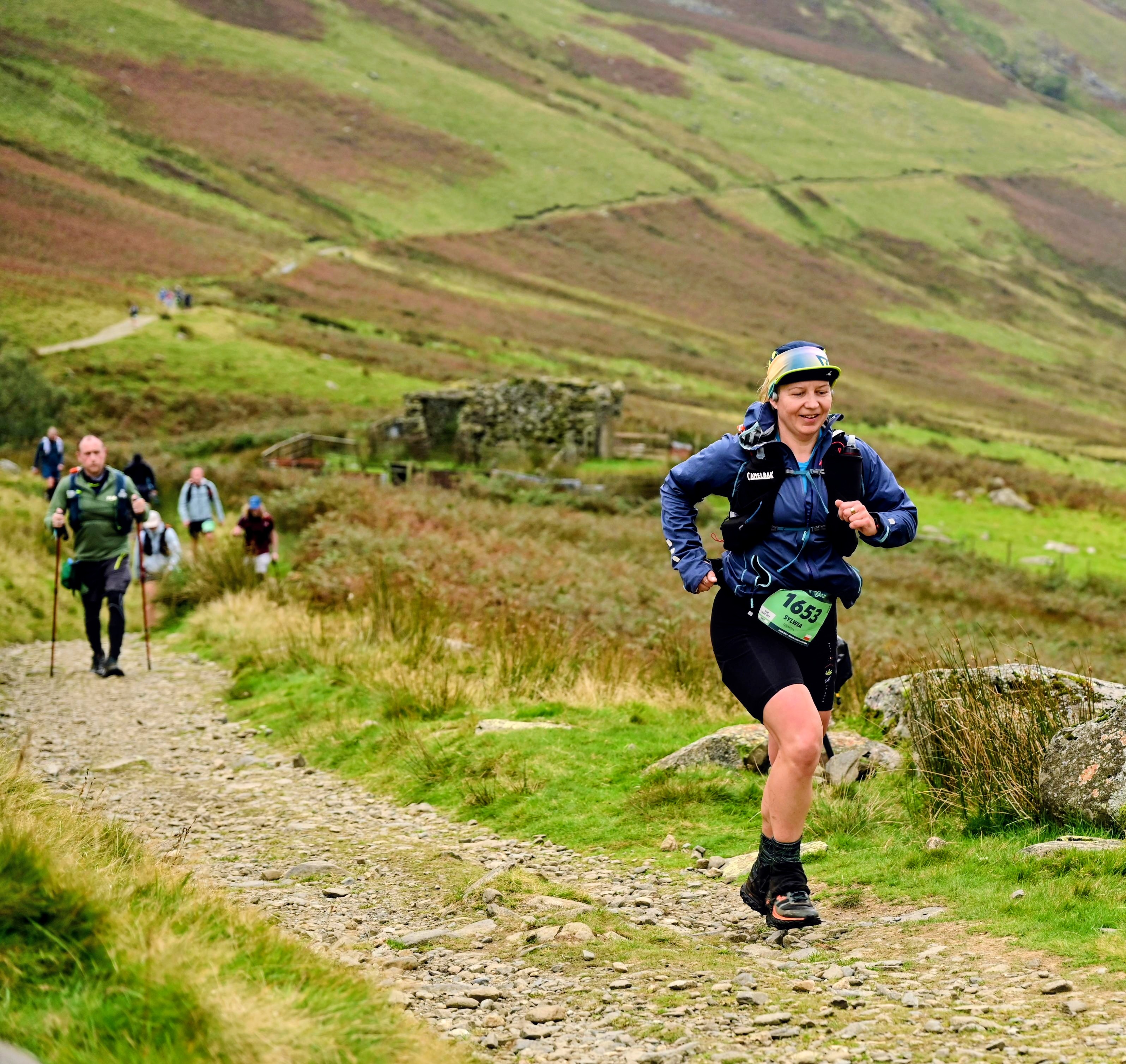Runner moving fast down a stony, uneven trail during a Lake District mountain ultra.