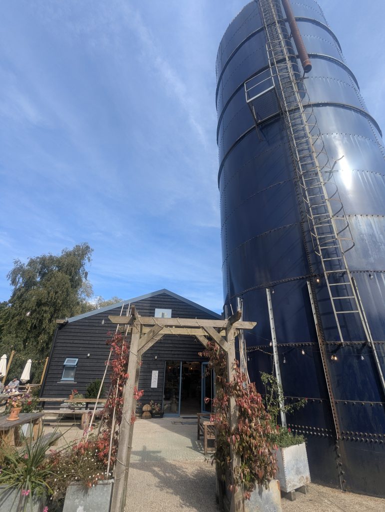 Tall iconic blue metal silo standing outside The Blue Silo micropub entrance with wooden archway in Selstead Kent