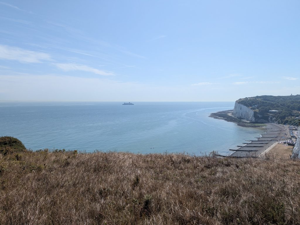 A breathtaking view looking down into the cove of St Margaret's Bay, framed by towering white chalk cliffs and the English Channel.