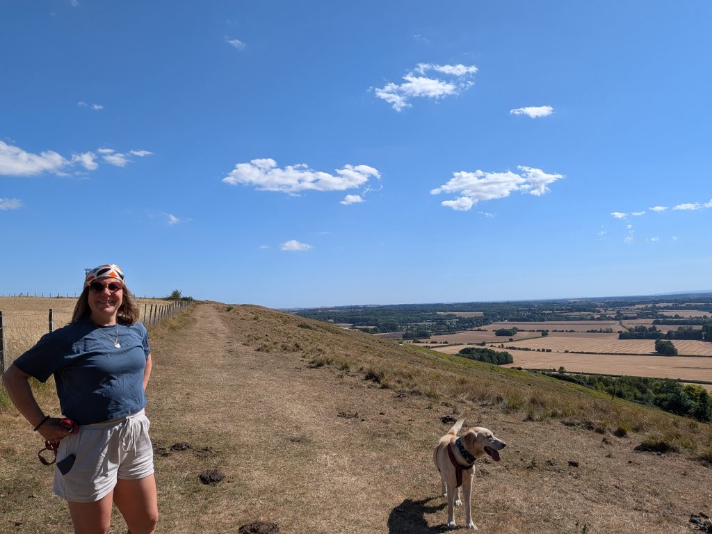Woman and Labrador walking on the sweeping chalk hills of the Wye Downs along the North Downs Way.